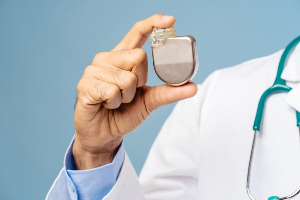 Doctor holding a pacemaker device, illustrating the risks associated with defective medical implants.
