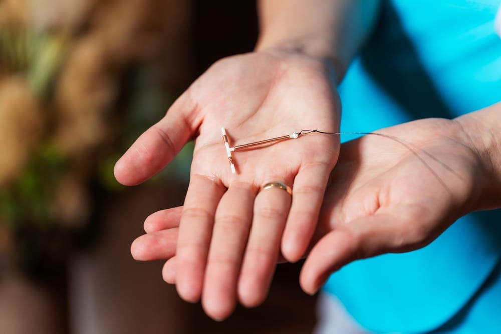 Close-up of a person holding a copper Paragard IUD in their hand, representing device breakage and related injury lawsuits.
