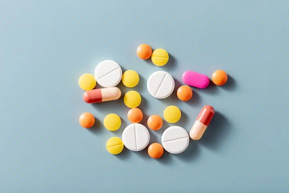 various colored pills with glass on blue background