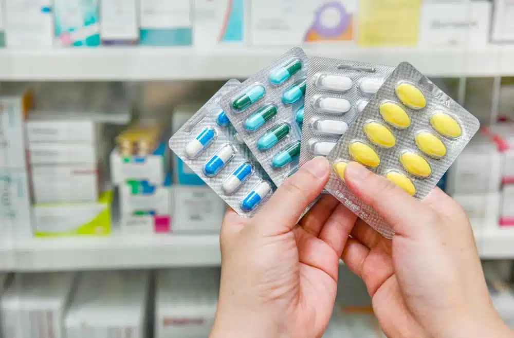 Hand holding medicine capsule pack at the pharmacy drugstore.